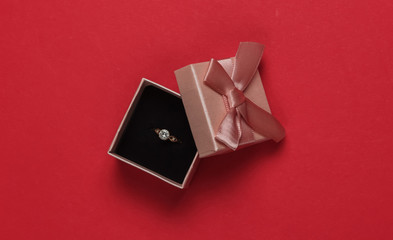 Gift box and engagement gold ring with diamond on a red background. Wedding, romantic concept. Jewelry. Top view. Flat lay
