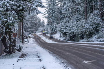 Snow-covered road with traffic in small town