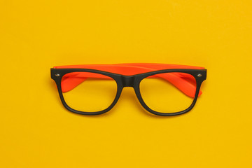 Stylish glasses without lenses on a yellow background. Top view