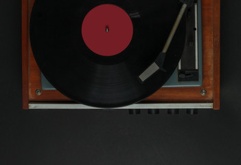 Retro music player. Vinyl record player with a vinyl record on a black background. 70s. Top view