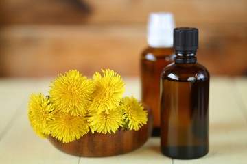 Dandelion tincture. Herbal tincture.  Medicinal tincture in brown glass bottles and dandelion flowers on a  wooden background.infusion of healing herbs. Homeopathy