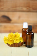 Dandelion tincture. Herbal tincture.   Medicinal tincture in  glass bottles and dandelion flowers on a  wooden background.infusion of healing herbs. Homeopathy