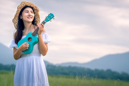 Asian girl playing musical instrument on meadow