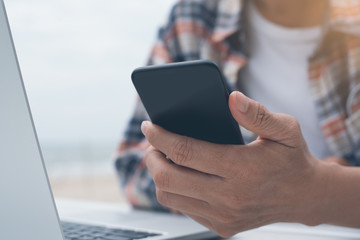 Man using smartphone and working on laptop computer