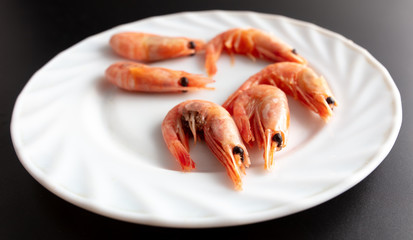 Red shrimp in a white plate on a black