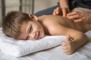 Obraz na płótnie Canvas Boy toddler relaxes from a therapeutic massage. Physiotherapist working with patient in clinic to the back of a child