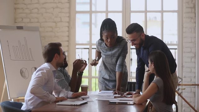 Confident biracial business woman instructing newbie intern in boardroom.