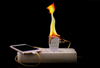 On fire adapter charger mobile at plug Receptacle on black background, Electric short circuit...