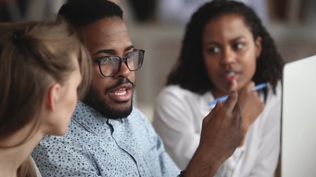 Smart biracial professional showing software to colleagues.