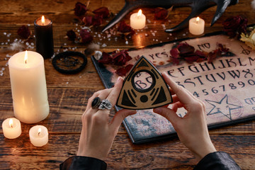 Mystic ritual with Devil's board and candles. The girl calls spirits.The mystical atmosphere of occultism and black magic.