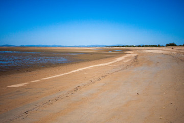 The coastal strip (coastline, beach) at low tide. A wide strip of beach with a desert area of wet sand. Makey, Queensland, Australia.