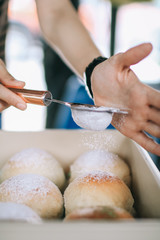 Homemade sweet buns with powdered sugar. Sweet breakfast.Close up view of baker is working.Tasty sweet buns with sweetened condensed milk, Thai tea custard on plate and icing sugar
