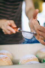 Homemade sweet buns with powdered sugar. Sweet breakfast.Close up view of baker is working.Tasty sweet buns with sweetened condensed milk, Thai tea custard on plate and icing sugar