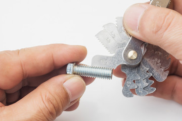 Hand of mechanic man holding Thread Measuring Gauge Screw Pitch Tool and gauging of thread on steel...