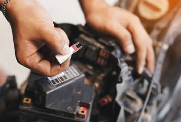 motorcycle mechanic replaces a fuse battery. motorcycle maintenance and service and repair concept...