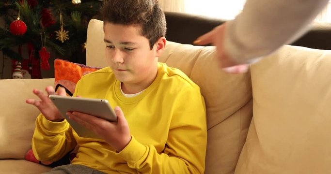 Mother hand take away tablet computer  but smart young boy taking smart phone to his stash . Technology and People Concept