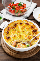 Fish pie with salmon, mashed potatoes, green peas and creamy sauce. on  wooden background.