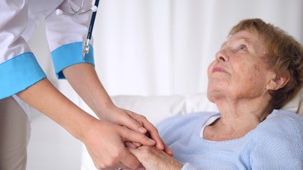 Doctor Reassuring Senior Patient Holding Hands. Elderly Health Care.