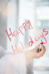 Hand of young female in white bathrobe writing regards with lipstick