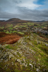 Beautiful colorful Autumn Fall landscape image of view from Loughrigg Brow towards mountains in distance with dramatic sky