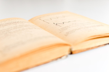 Close up shot of an open old science book containing equations and graphs from different fields: math, physics, chemistry. The pages have the marks of the past as they got orange.