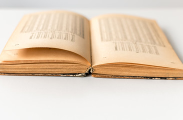 Close up shot of an open old science book containing equations and graphs from different fields: math, physics, chemistry. The pages have the marks of the past as they got orange.