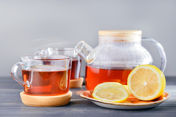 Time for tea, tea cups, teapot with hot tea and lemon on table.