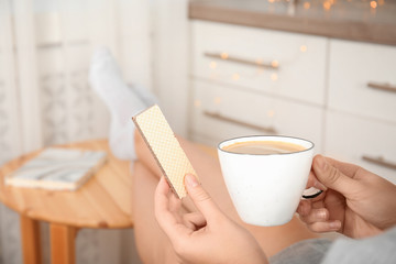 Woman having delicious wafer and coffee for breakfast indoors, closeup