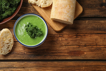 Tasty kale soup on wooden table, flat lay. Space for text