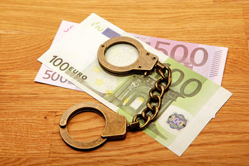 money banknote handcuffs wooden desk background 