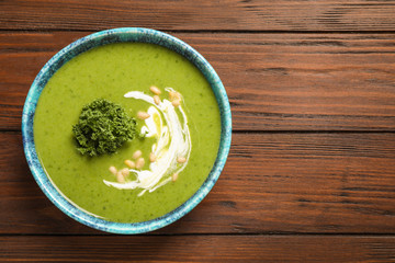 Tasty kale soup with pine nuts on wooden table, top view. Space for text