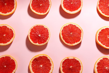 Tasty ripe grapefruit slices on pink background, flat lay