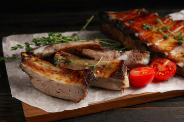 Tasty grilled ribs on black wooden table, closeup