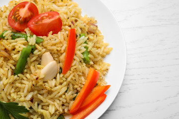 Tasty rice pilaf with vegetables on white wooden table, closeup