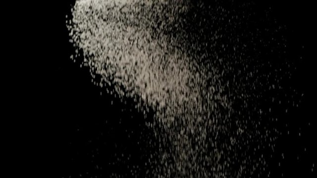 Slow motion of sifting falling down in spiral shape against black background