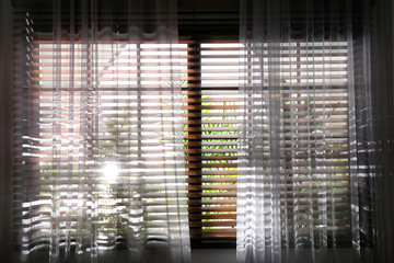 Window with beautiful curtains and blinds, closeup