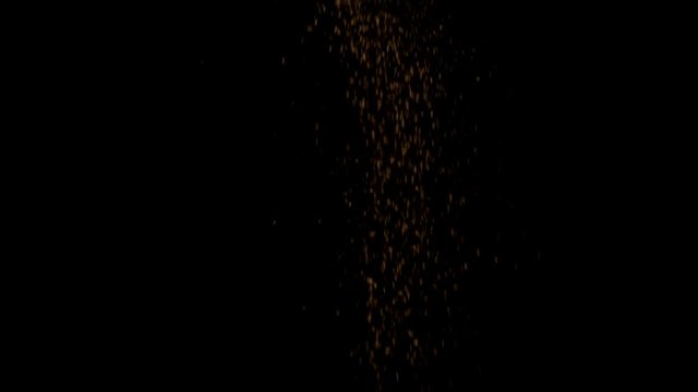 Slow motion of sprinkling brown cinnamon powder falling down against black background
