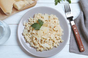 Delicious risotto with cheese on white wooden table, flat lay