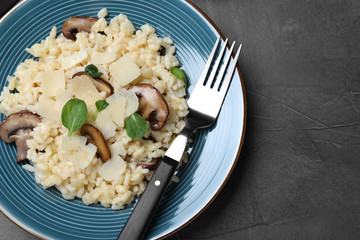 Delicious risotto with cheese and mushrooms on dark grey table, top view