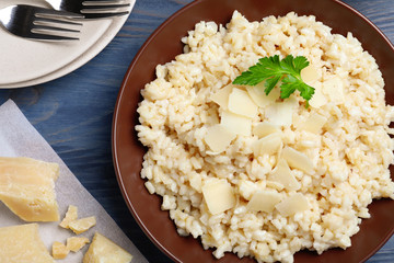 Delicious risotto with cheese on blue wooden table, flat lay