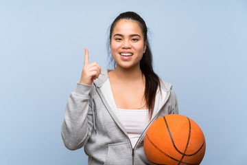Young Asian girl playing basketball over isolated background pointing up a great idea