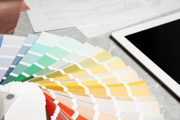 Palette samples and tablet on grey marble table, closeup. Designer's workplace