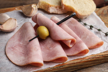 Slices of tasty ham with olive on table, closeup