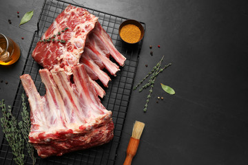 Raw ribs with thyme and pepper on black table, flat lay