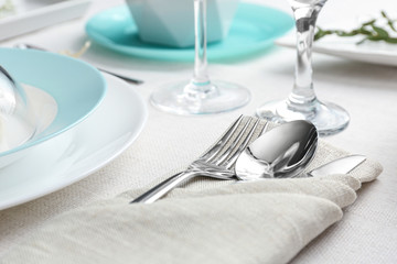 Elegant cutlery with green leaves on table, closeup. Festive setting