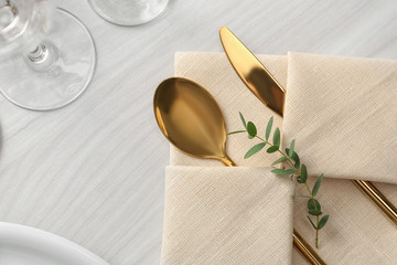 Elegant cutlery with green leaves on table, flat lay. Festive setting