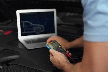 Mechanic with laptop doing car diagnostic at automobile repair shop, closeup