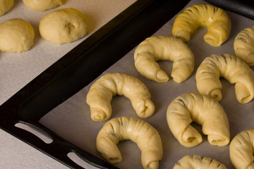 Raw croissants on metallic oven-tray closeup.Croissants with raw dough.