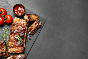 Delicious grilled ribs on black table, flat lay. Space for text