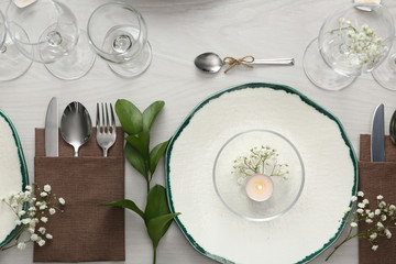 Elegant table setting with green plants on white wooden background, flat lay
